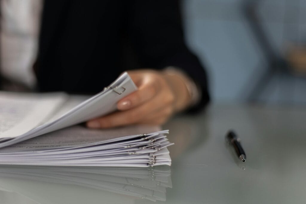 pexels-photo-6077600-6077600-1 Close-up of a professional organizing a stack of documents on a desk.